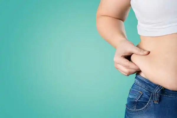 Image of woman pinching her love handles to show weight gain Bicester